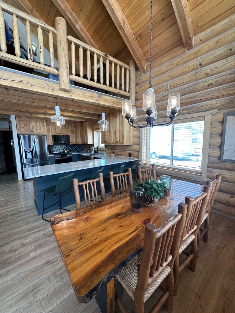 Rustic wooden dining table next to modern kitchen in log cabin in Dutch John, Utah